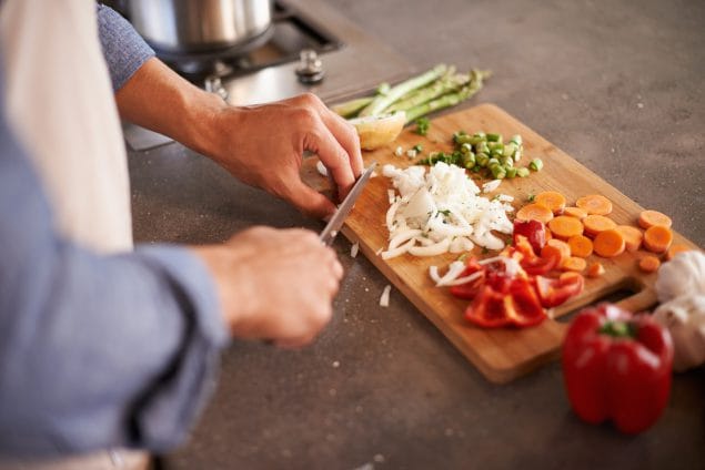 Close of a person chopping veggies on a wood board