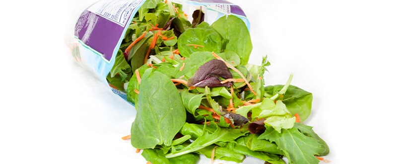 Packaged salad mix over a white background.