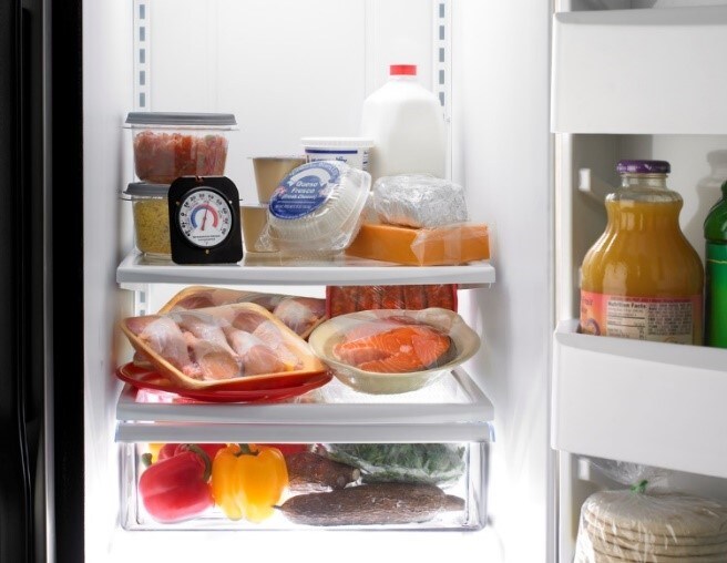 PHoto of a refrigerator with common graceries found inside including fruits, vegetables, and various meats.