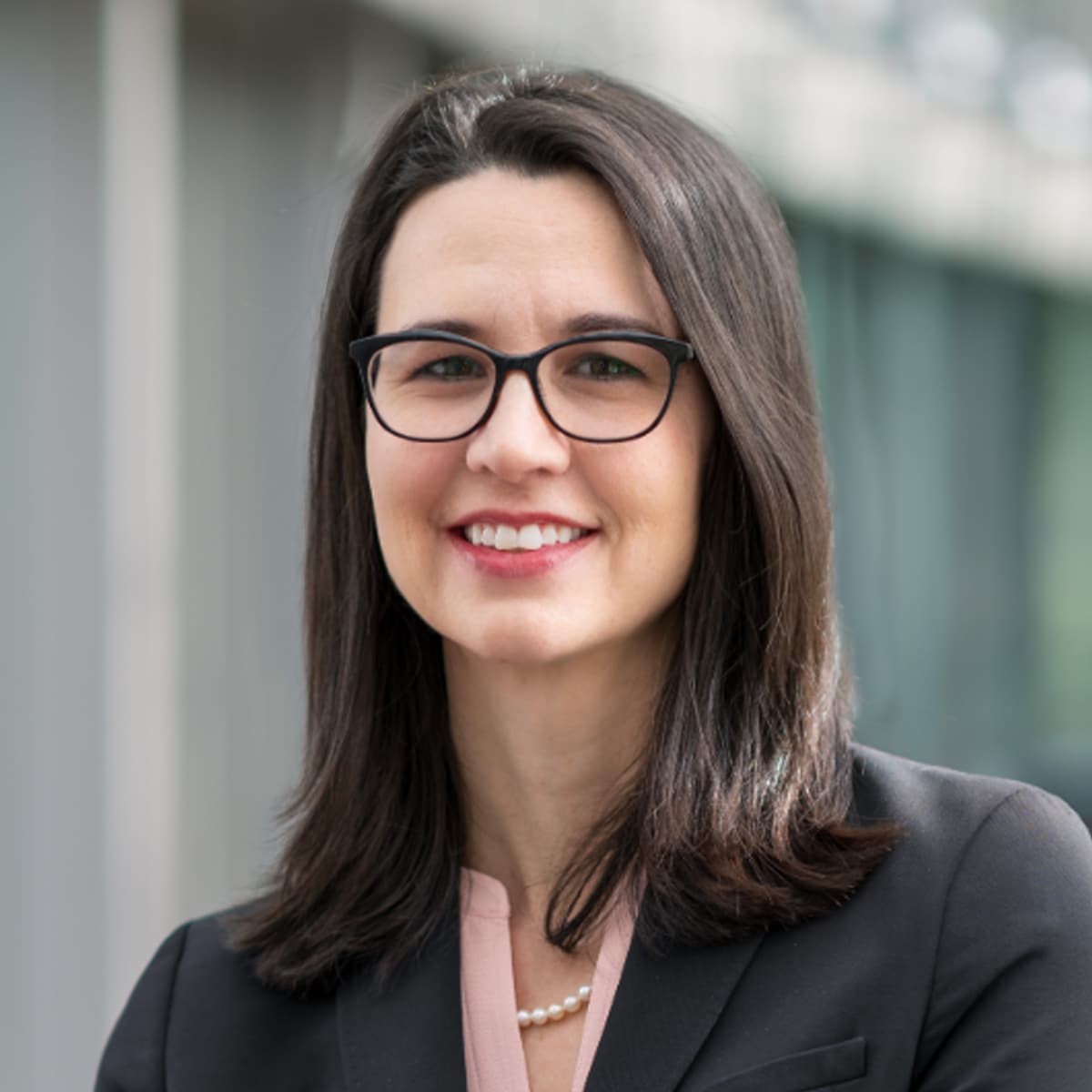 Adrienne Keen, Ph.D., is the director of the Inform division for the Center for Forecasting and Outbreak Analytics, has shoulder-length brown hair and is wearing glasses with a black suit jacket.