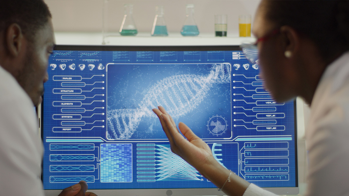 Two public health professionals looking at a double helix on a computer monitor