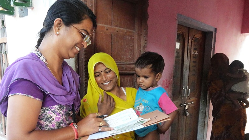 Image of a woman conducting a survey with a mother and child