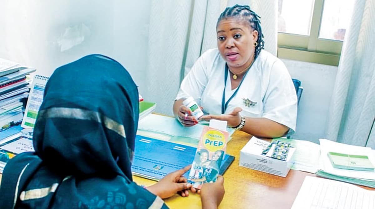 In Tanzania, a health care worker presents PreP information to woman. Both women are sitting in an office across a desk.
