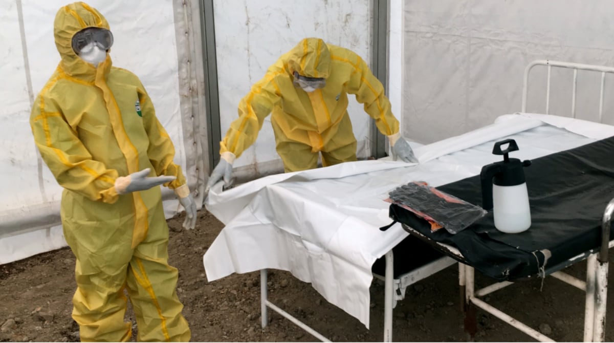 Two health care workers in yellow personal protective equipment