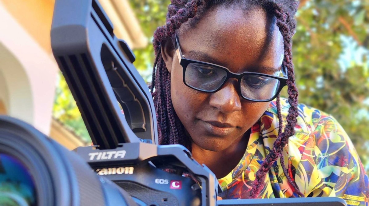 Woman wearing glasses managing a video camera.