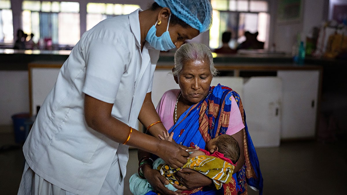 A woman in India holds her grandchild as a health worker gives the baby a hepatitis B birth dose.