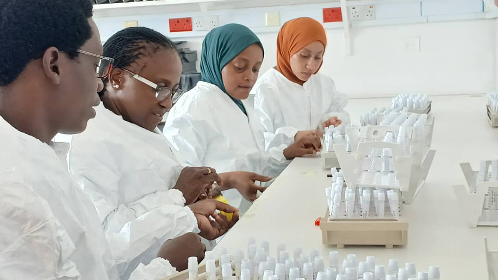 Four scientists in white coats labeling tubes