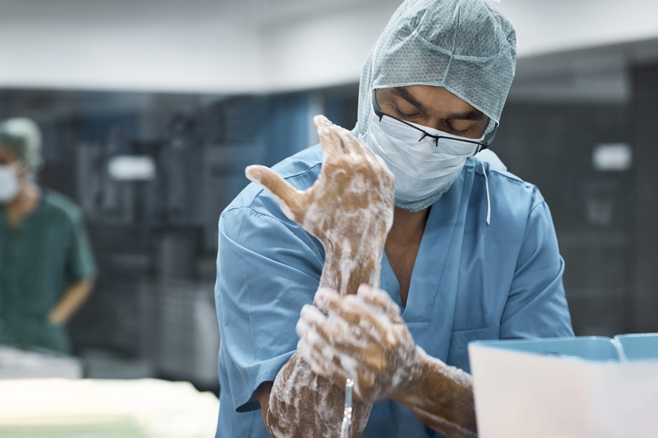 A healthcare worker wearing a mask lathers his hands with soap.