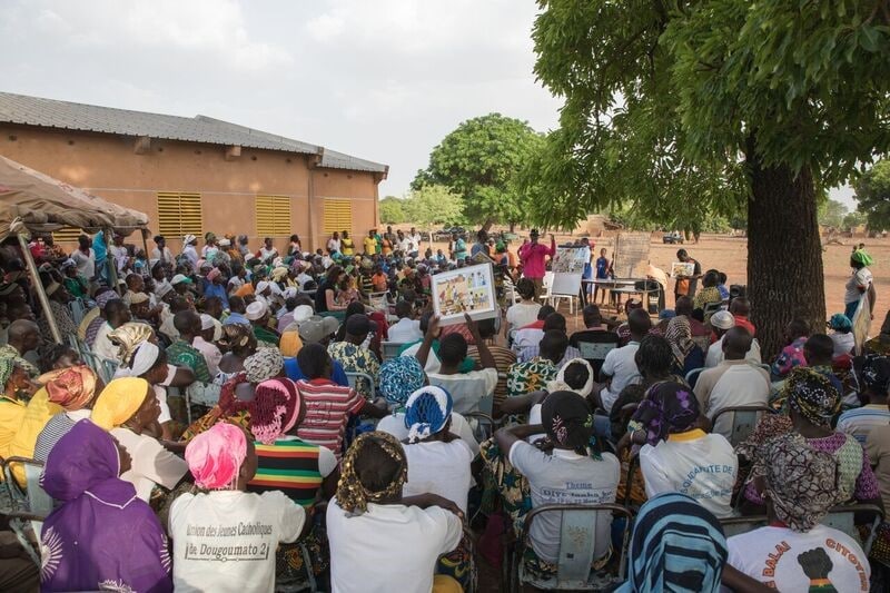 Villagers from Dougoumato listen to a presentation about disease identification. The session is designed to broaden the ability of Burkina Faso to detect disease and is just one element of a larger initiative supported by CDC to strengthen disease detection, response, and prevention in a key disease corridor in West Africa. (Source: Evelyn Hockstein, CDC/Foundation)