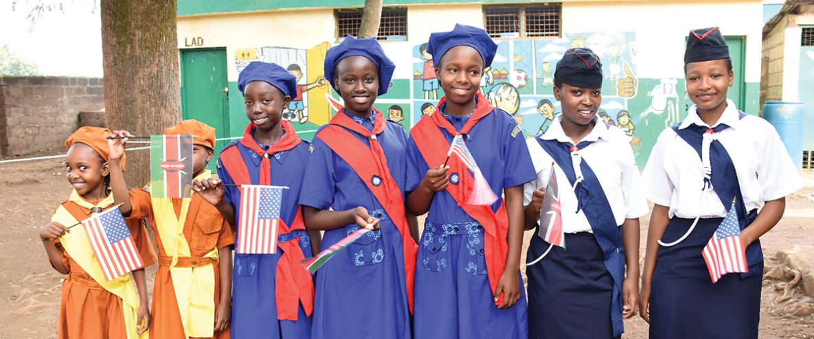 Kenyan Girl Guides waving flags from the U.S.A. and Kenya