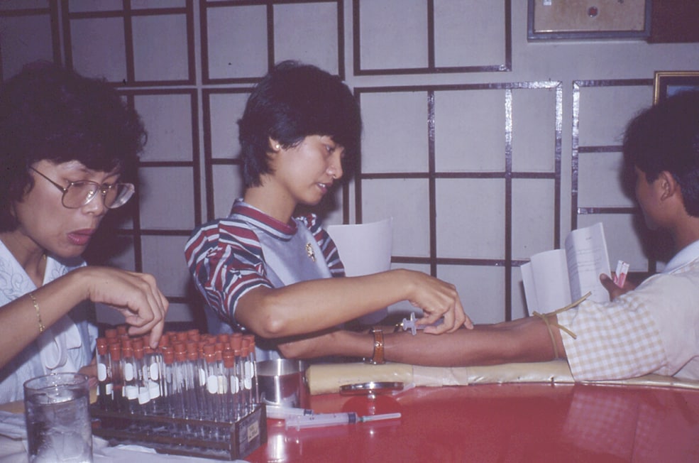 Collection of serum in Patpong from male sex worker for the first large HIV prevalence survey in Thailand in 1985 (for testing by Abbott kit furnished by CDC), conducted by Thai FETP. Photo: Bruce G. Weniger, MD, MPH; CAPT, USPHS/CDC (ret.)