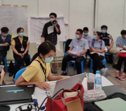 Dr. Ern with Department of Disease Control Thailand staff and healthcare personnel during a COVID-19 outbreak daily briefing