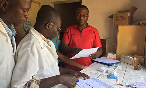 FETP resident Gauthier Mubenga reviewing data collection forms with laboratorians at the Yomou prefectural hospital in N%26rsquo;Z%26eacute;r%26eacute;kor%26eacute;, Guinea