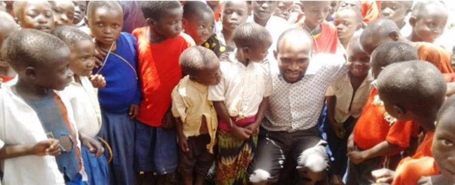 Disease detective John Gwakisa with pupils from Kajana primary school