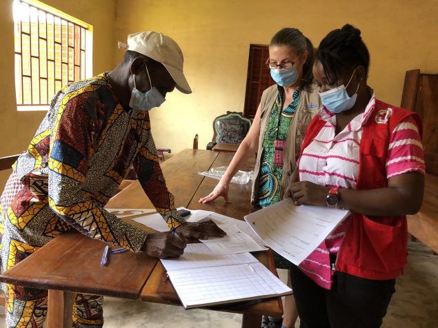 Guinean Red Cross workers and CDC health communicator, check community feedback data from the Gouecké health center