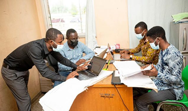 A group of four men that are part of a data collection team work in an office in a hospital in Ghana, 2021.