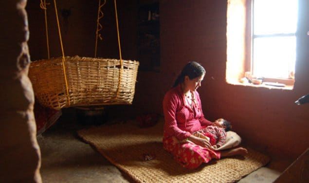 Woman holds sleeping infant in her lap, Nepal 2009.