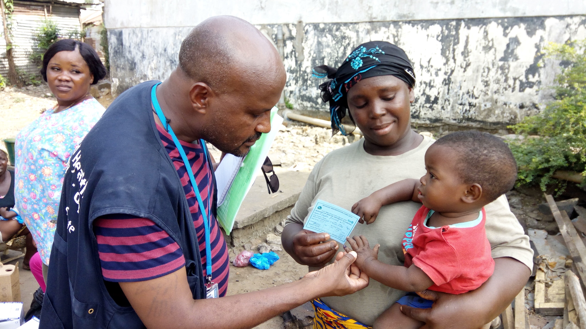 Un participant STOP examine la carte de vaccination et l’état vaccinal d’un enfant au Libéria
