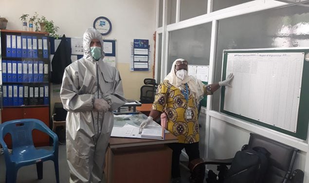 Um consultor do STOP em equipamentos de proteção individual revisa dados em um escritório com um profissional de saúde usando uma máscara facial.