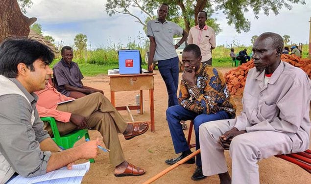 Un consultant STOP discute avec des membres de la communauté en plein air au Sud-Soudan.