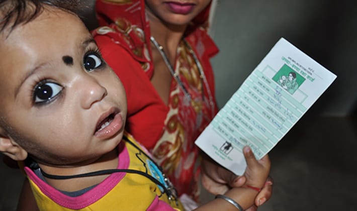 A child holding his vaccination card at a health facility in Rajasthan, India.