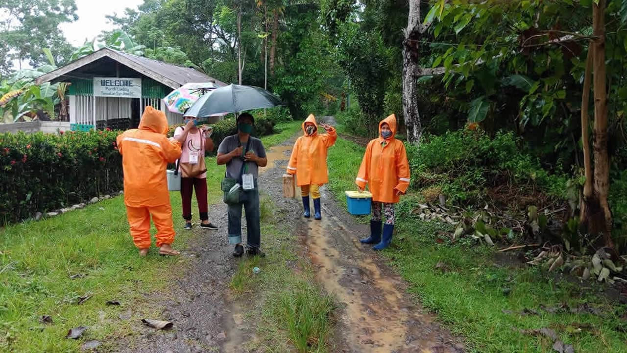 Health workers carry vaccines through the rain in the Philippines.
