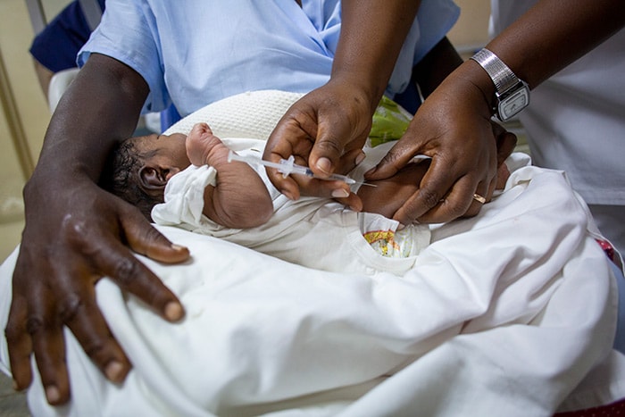 A mother in Angola holds her newborn baby as he receives vaccines against hepatitis B and tuberculosis.