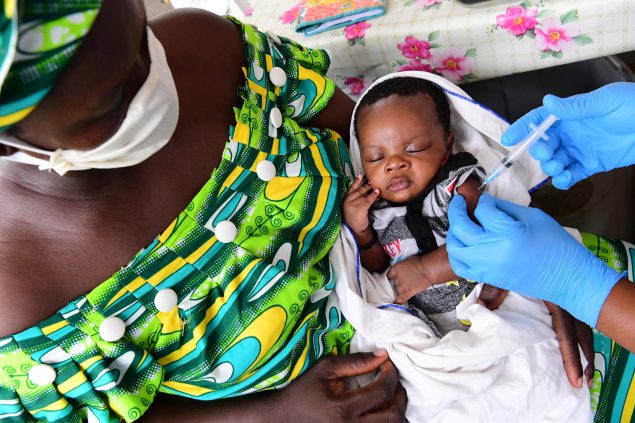 Woman holding a baby who is receiving a vaccine in Côte dʼIvoire, 2020.