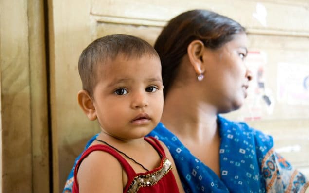 Child waiting for a vaccine in mother's arms (India).