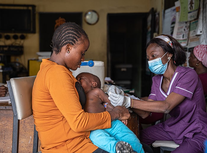 A health worker administers a dose of measles vaccine to a child in Nigeria.