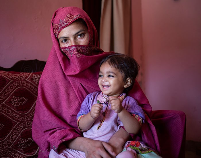 A mother in Pakistan brings her young daughter to get a second dose against measles along with other routine vaccinations.