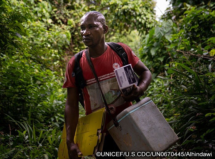 A male nurse carries vaccines and supplies along a jungle trail in Democratic Republic of the Congo.