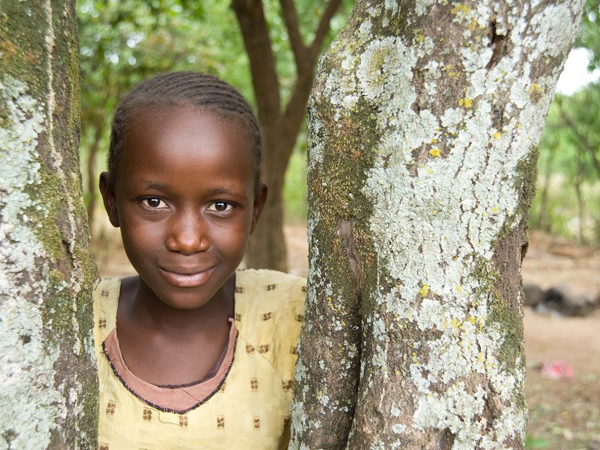 A girl leans against a tree in the village of Usoma, Kenya.