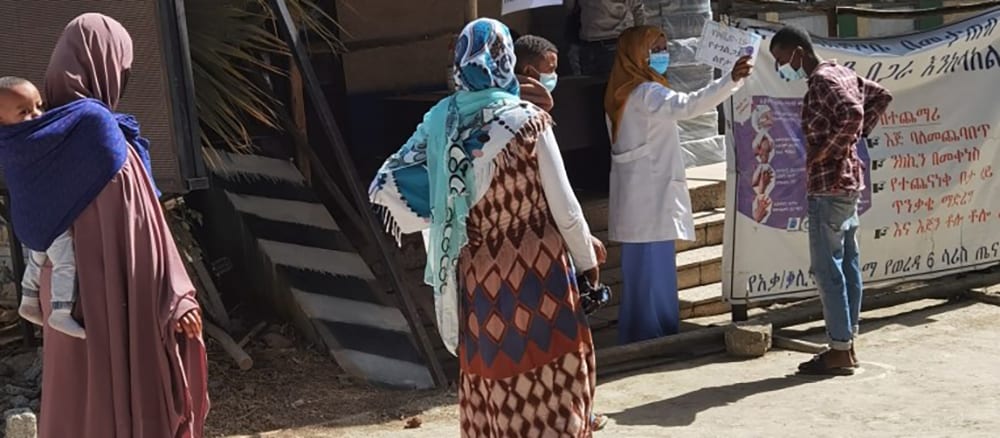 Individuals and families are waiting in line to be screened for COVID-19 in Ethiopia.