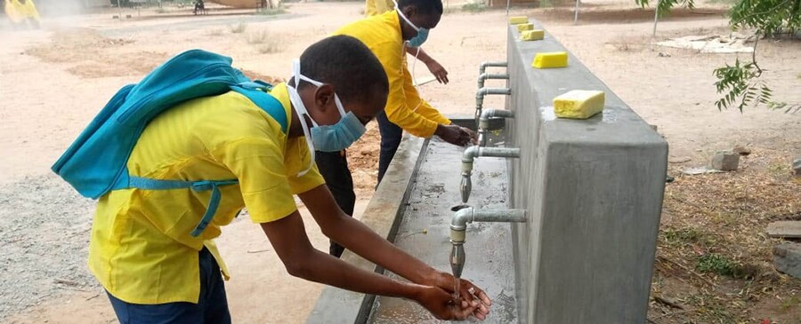 Three boys using a handwashing station constructed at the Wadarji