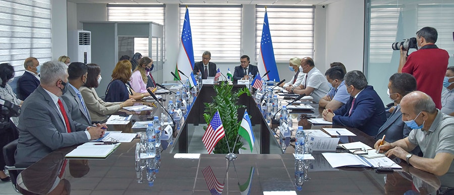 Conference room of people with the flags of the Republic of Uzbekistan and the United States of America
