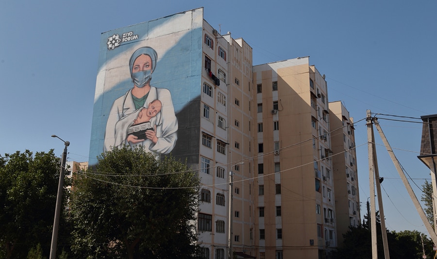Mural on the wall of a building shows a healthcare provider wearing personal protective equipment and holding a baby