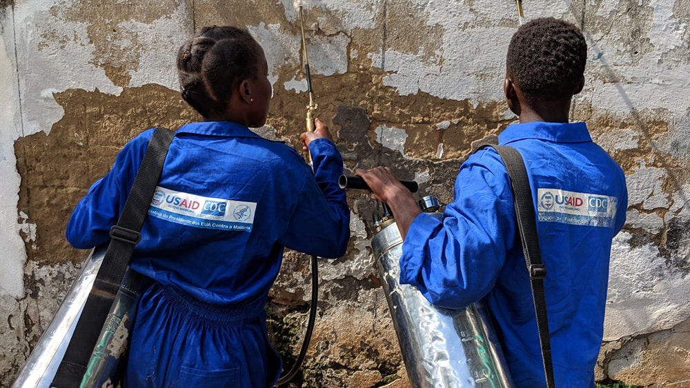 Two PMI staff members coat the walls with insecticide to kill mosquitoes and prevent malaria.