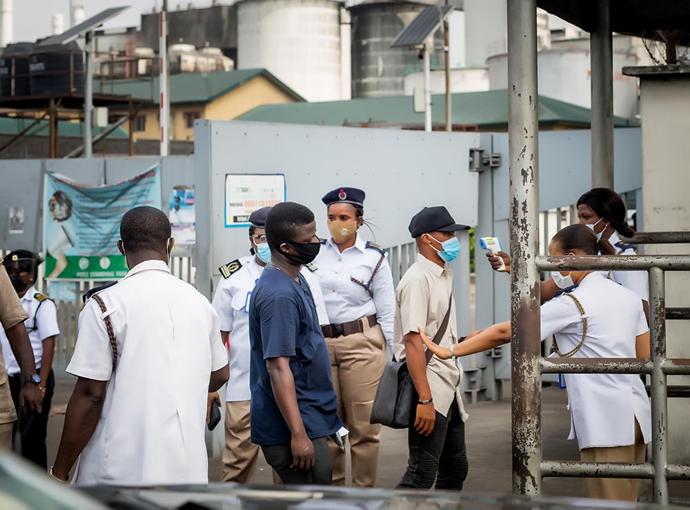 Photo of Port Health Services officers at the Apapa Sea Port checking the temperature of a visitor using an infrared thermometer.