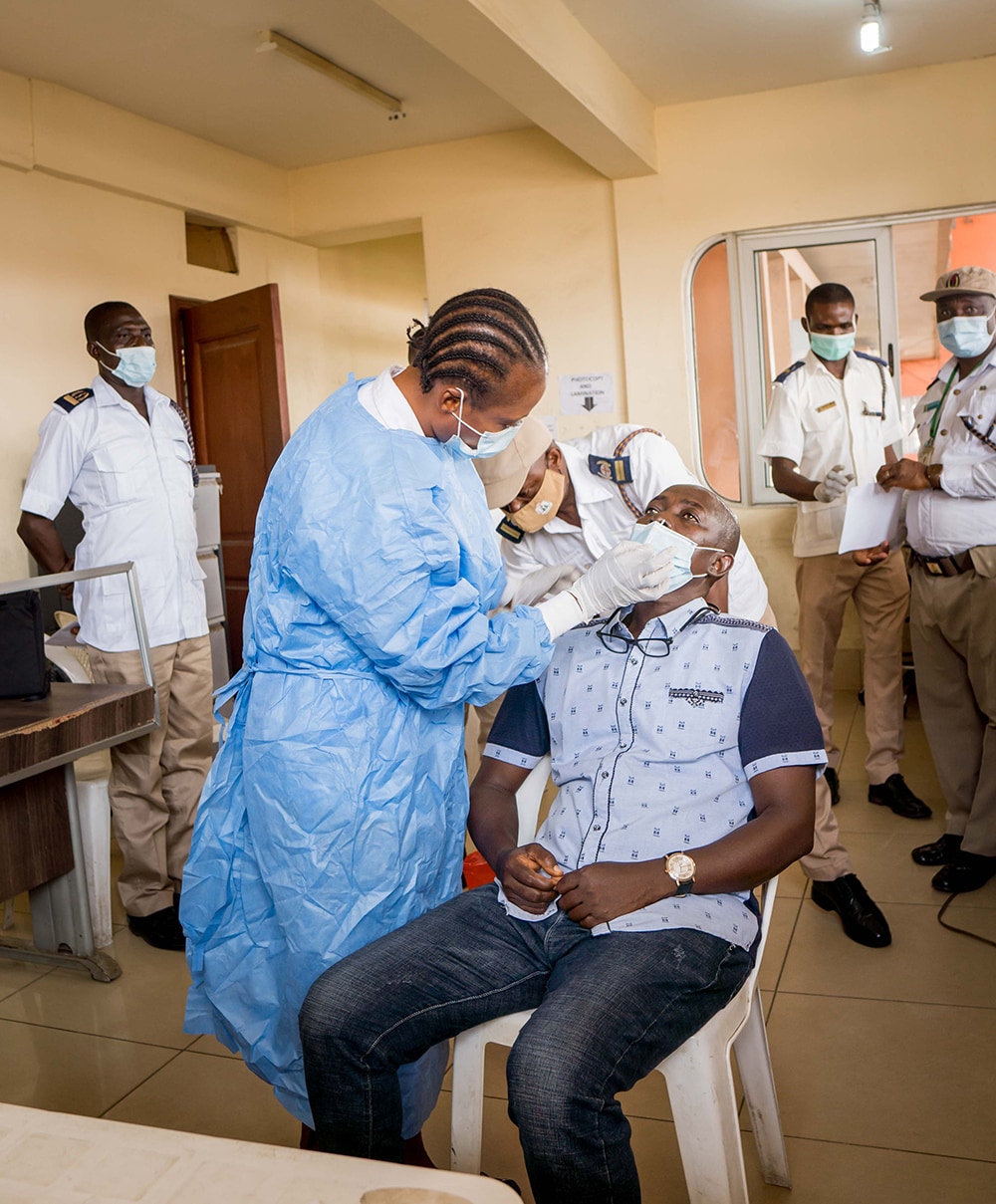 Photo of a Port Health officer conducting a COVID-19 rapid diagnostic test on a passenger at the Seme Krake border in Nigeria.