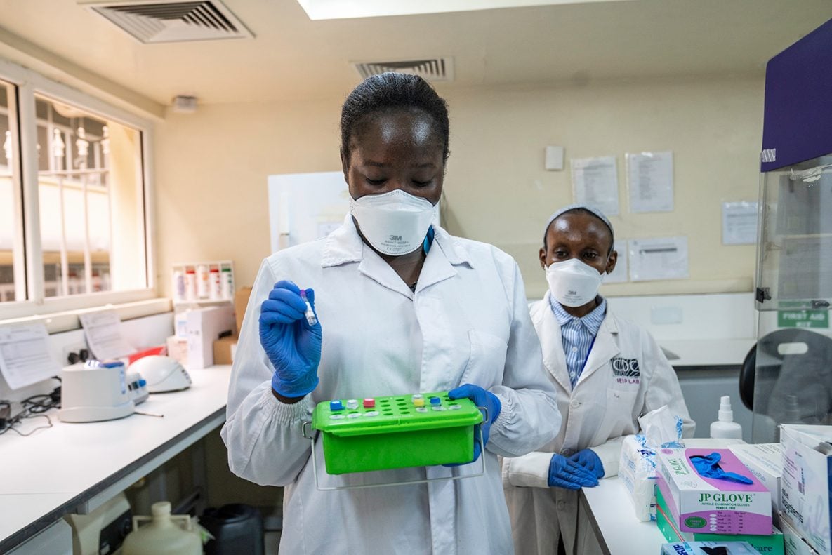 Photo of two CDC Kenya laboratory workers. One person is holding a tray of samples for testing.