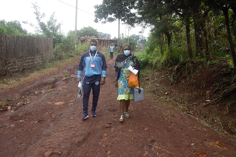 Photo of two public health professionals walking in a rural setting to see patients in their communities.
