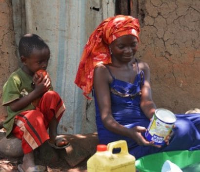 Kabugho washes utensils with her 5yrs old son in front of her house. 