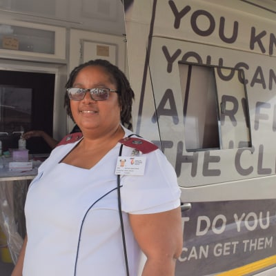 healthcare worker stands next to mobile outreach van