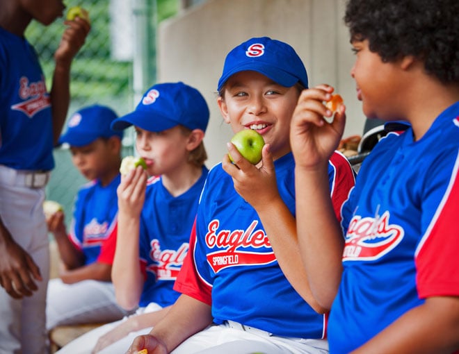 Boys' baseball team eating apples