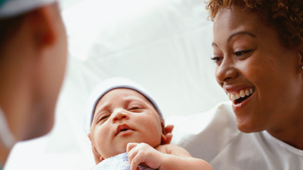 Nurse handing newborn to mother.