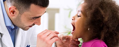 A doctor examines a young girl’s throat