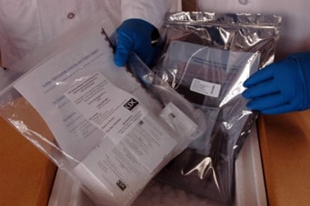 Picture of laboratory person handling packages of RT-PCR test kits.