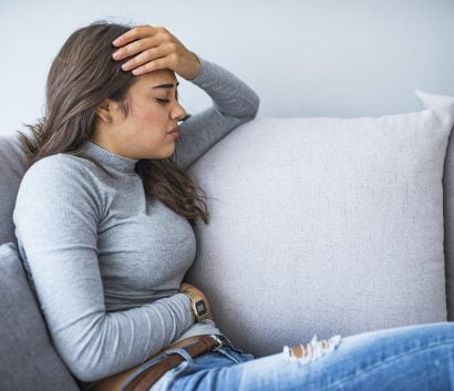 Young woman sitting on a couch feeling ill