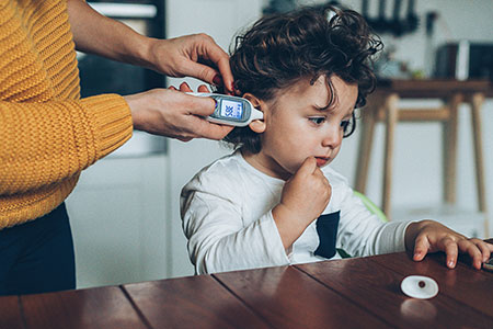 Mother takes child's temperature using a digital thermometer